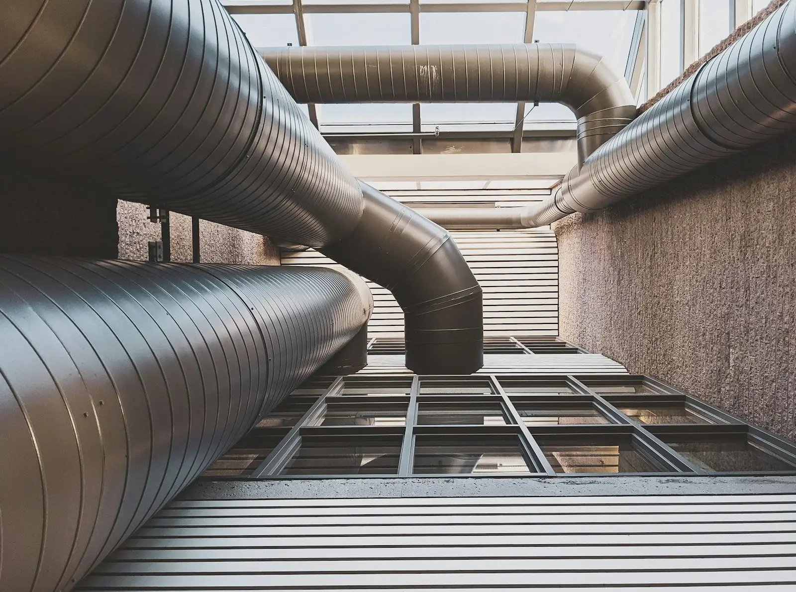 Weathered, grease-darkened exhaust pipework on a commercial building, overdue for cleaning