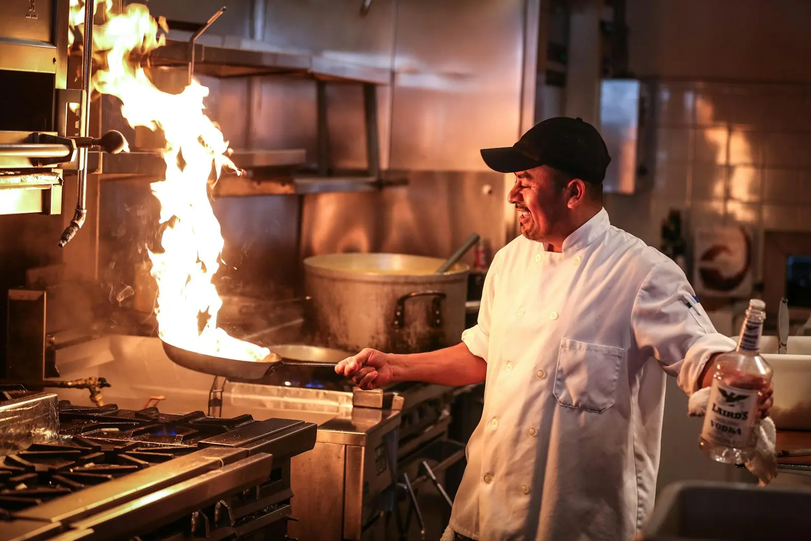 Flames rising from a commercial cooktop beneath an extraction canopy