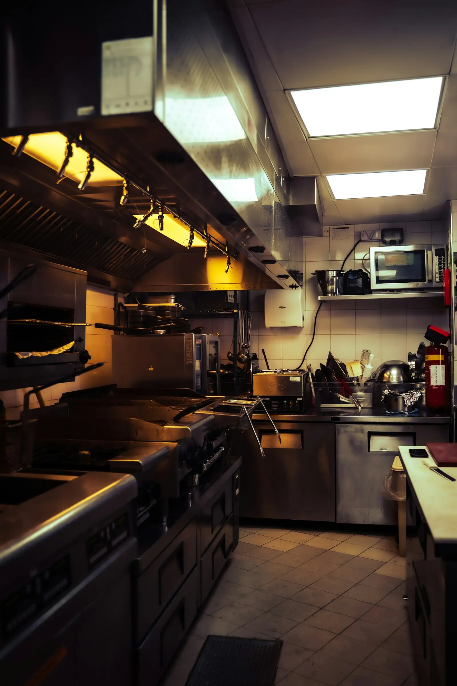 Stainless steel commercial kitchen with extraction canopies above the cooking line