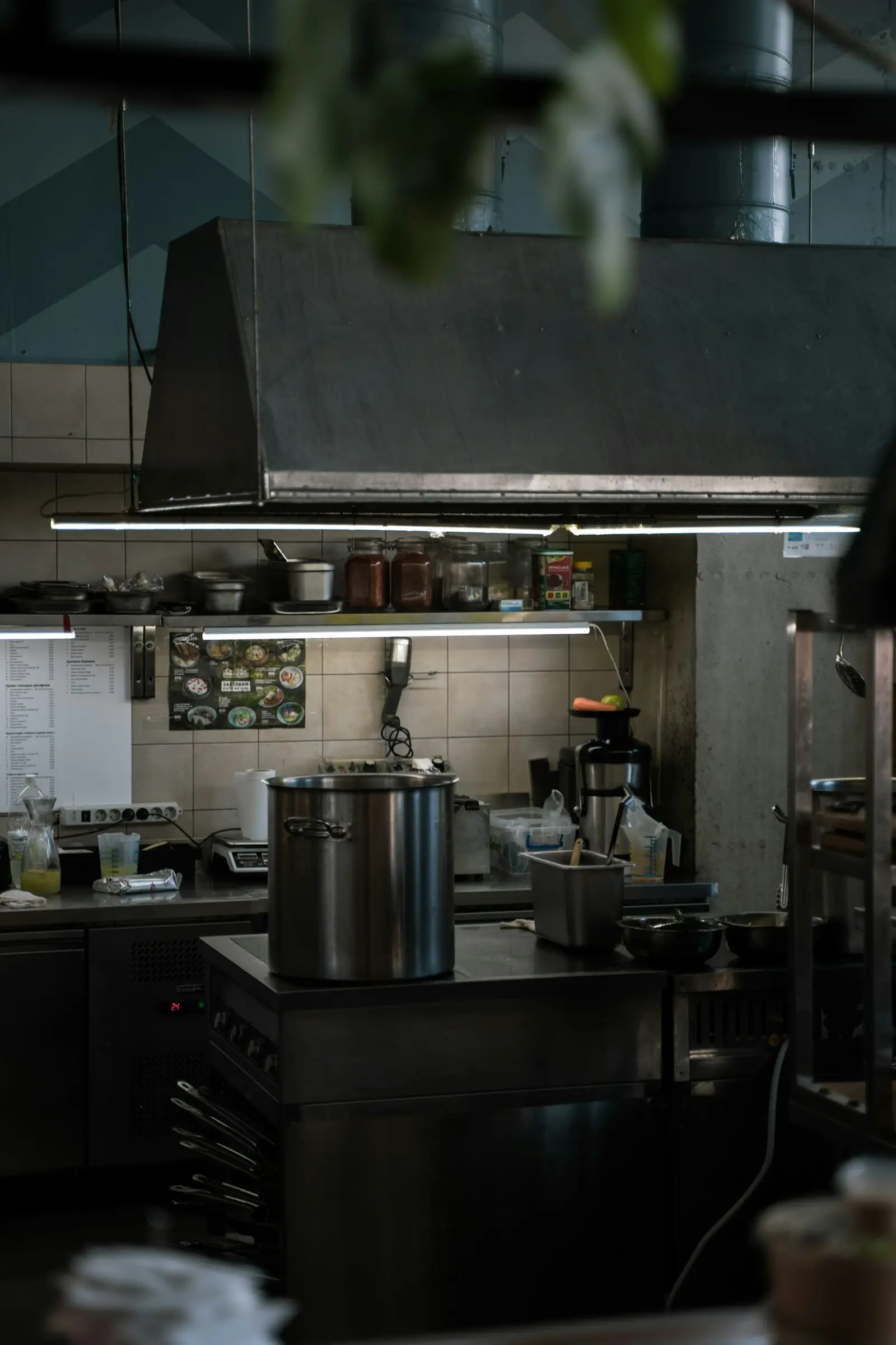 Stainless steel pots on a commercial gas cooktop beneath an extraction canopy