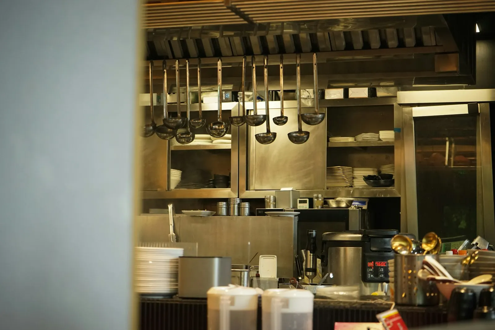 Clean utensils and pans hanging on a rail beneath a commercial extraction canopy