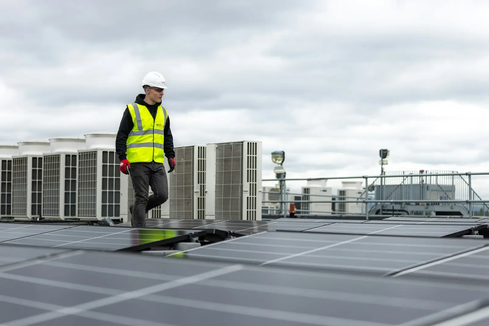 Technician in hi-vis walking between rooftop extraction plant on a commercial building